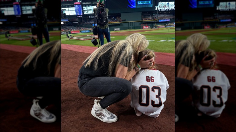 Erika Kirk kissing her child at Chase Field while wearing metallic sneakers