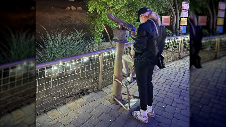 Erika Kirk in a black sweat suit with grey sneakers looking out of telescope
