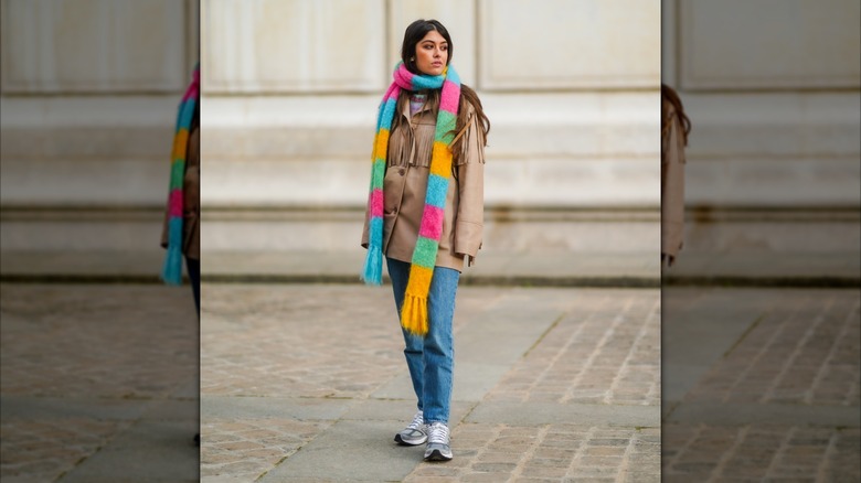 A woman with a bright scarf over a camel trench coat