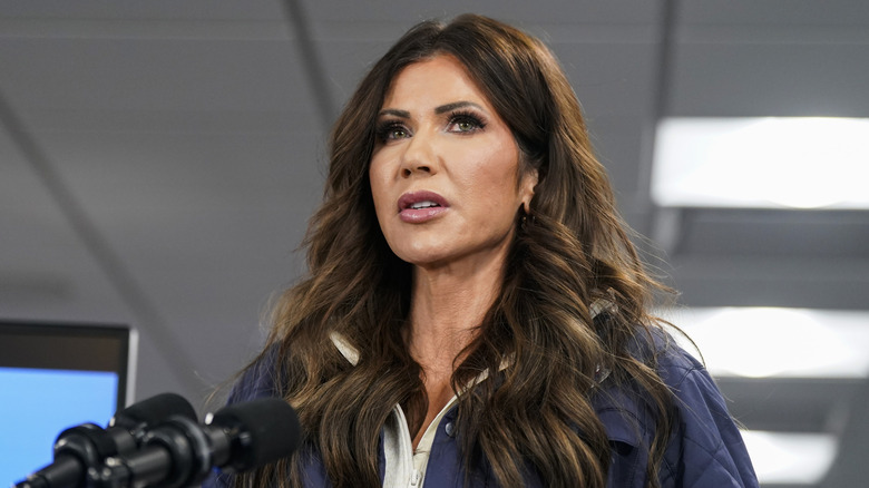 Kristi Noem in a blue jacket in front of a microphone