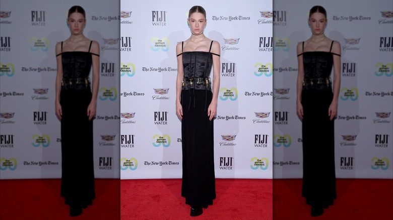 Hunter Schafer posing in a black dress with padlocks at the Gotham Awards