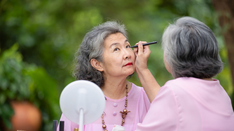 Women applying makeup on her friend, both wearing pink tops