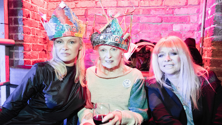 Pamela Anderson sitting alongside Vivienne Westwood and Jo Wood while wearing a handmade-looking crown