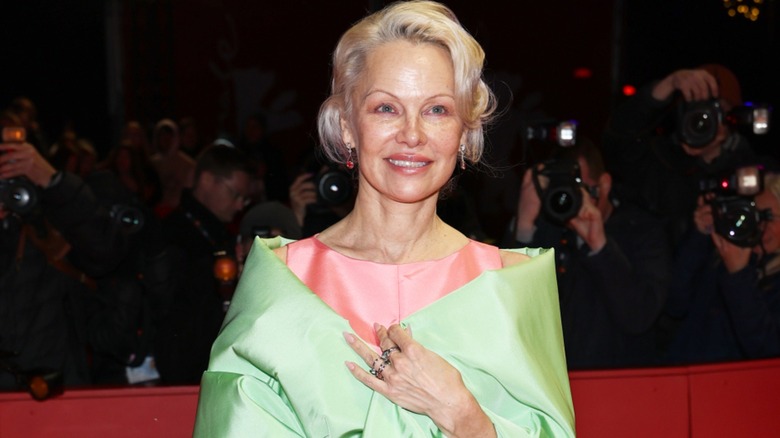 Pamela Anderson in a pink dress and a green shawl at an event