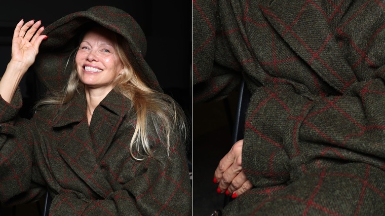 Pamela Anderson with a plaid coat and hat on and bright red nails
