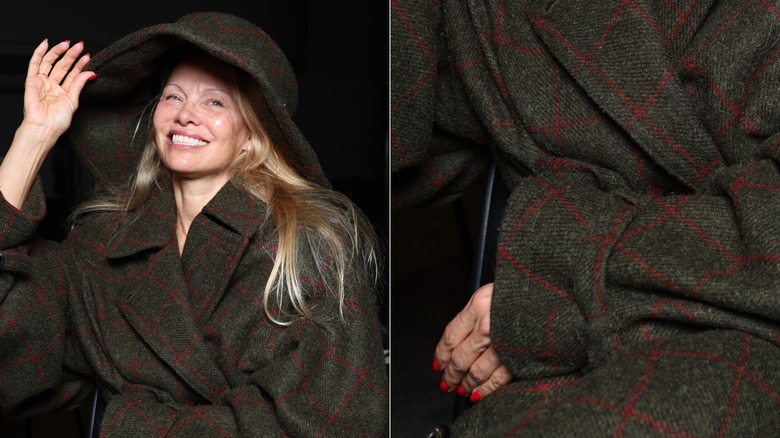 Pamela Anderson with a plaid coat and hat on and bright red nails