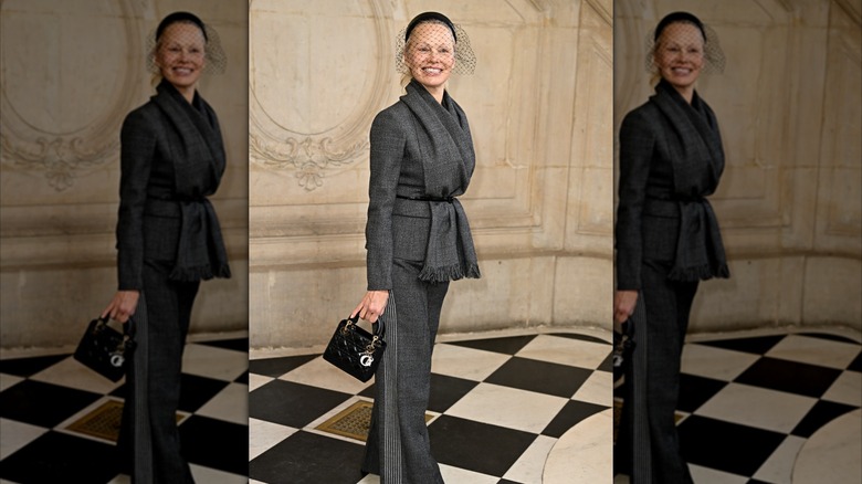 Pamela Anderson in a gray suit with a birdcage headpiece