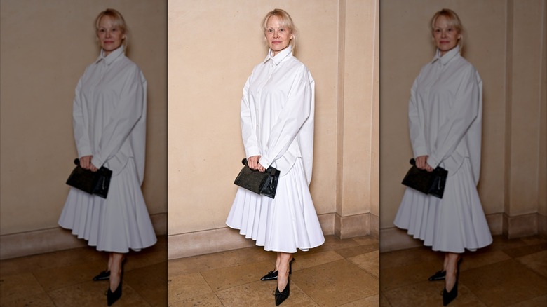 Pamela Anderson in a white pleated skirt and white shirt at an event