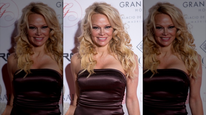 Pamela Anderson in a brown strapless gown at an event with long blond hair