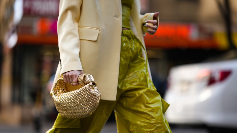 Woman seated, holding up shopping bag