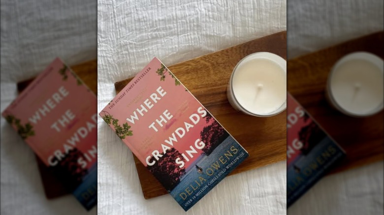 A flat lay of a copy of "Where the Crawdads Sing" next to a candle