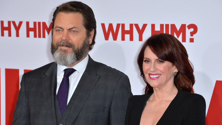 Megan Mullally wearing a black blazer and Nick Offerman wearing grey suit with a purple tie