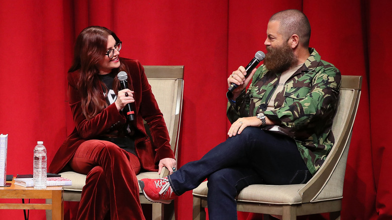 Megan Mullally wearing red velvet suit and Nick Offerman in camo print