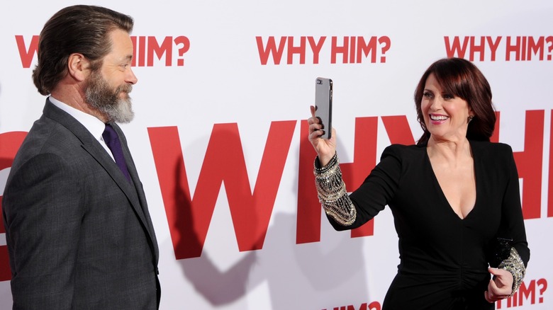 Megan Mullally wearing a black blazer and Nick Offerman wearing grey suit with a purple tie