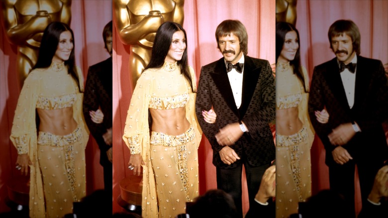 Cher (L) links arms with Sonny Bono (R) wearing a gold encrusted two-piece