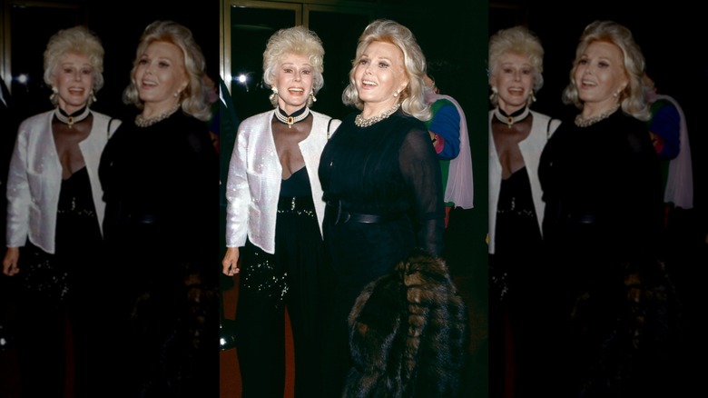 Eva Gabor (L) smiles wearing a pearl choker next to Zsa Zsa Gabor (R) wearing a crystal necklace