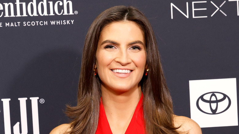 Kaitlan Collins wearing a red dress and red earrings on a red carpet