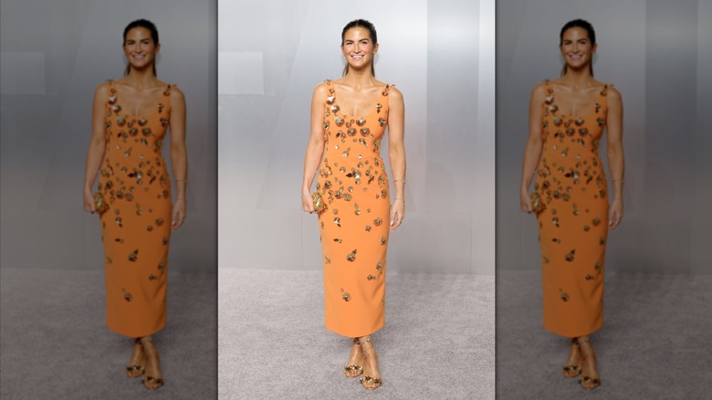 Kaitlan Collins smiles wearing an embellished orange dress