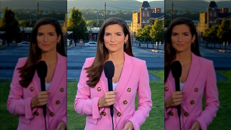 Kaitlan Collins holds a microphone wearing a pink blazer