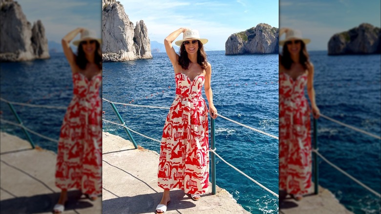 Kaitlan Collins smiles wearing a fedora hat and a pattered red and white maxi dress