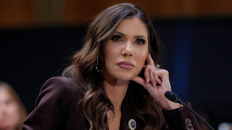 Kristi Noem with her hand on her jaw and a serious expression