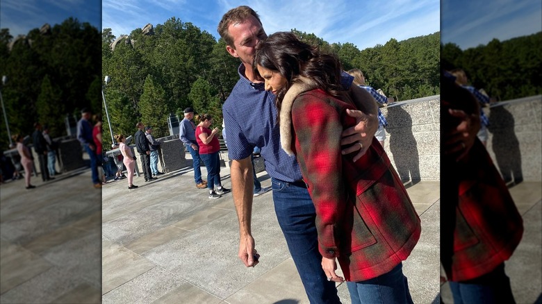 Bryon Noem kissing Kristi Noem on the head with his arm around her while outside