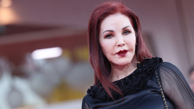 Priscilla Presley attending a film festival while wearing dark red lipstick and a black top