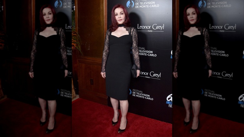 Priscilla Presley wearing a black dress with lace sleeves at a red carpet event