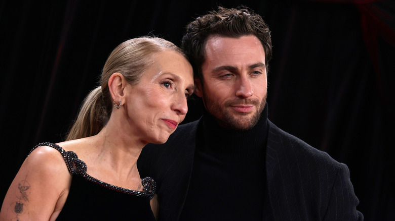 Sam Taylor-Johnson wears her hair slicked back and stands next to Aaron Taylor-Johnson smoldering