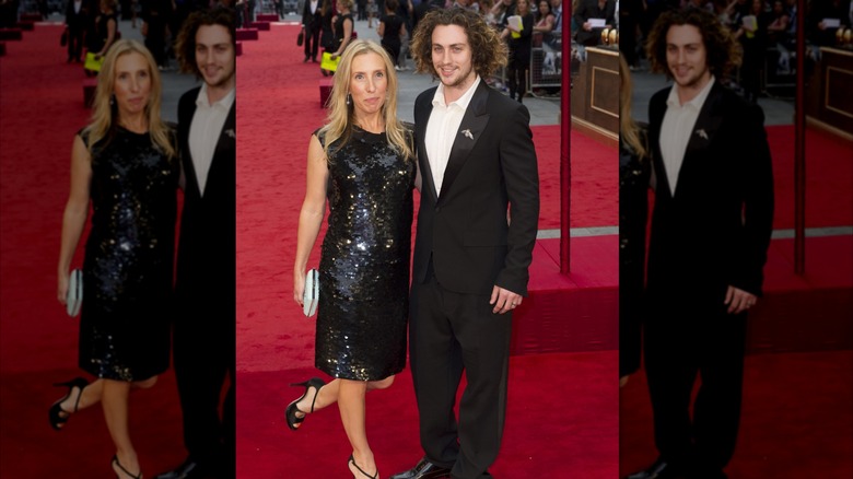 Sam Taylor-Johnson wears a black shiny dress next to Aaron Taylor-Johnson in a suit