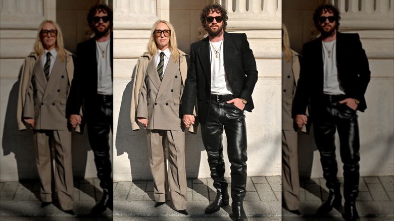 Sam Taylor-Johnson wears a suit and sunglasses next to Aaron Taylor-Johnson in leather trousers
