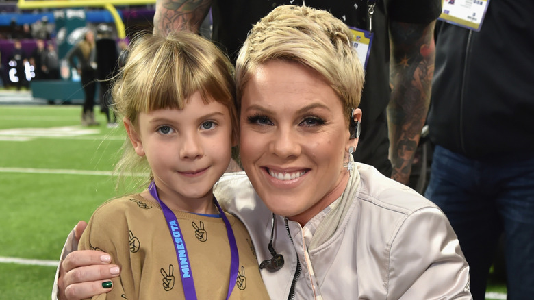 Singer Pink kneeling to pose with her daughter Willow Hart at the Super Bowl LII Pregame show in 2018