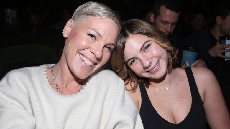 Pink and her daughter Willow Hart leaning their heads together and smiling while seated at the
