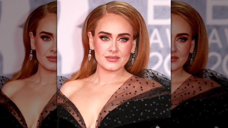 Close-up of Adele posing on the red carpet while sporting an orange-toned makeup look including winged eyeliner