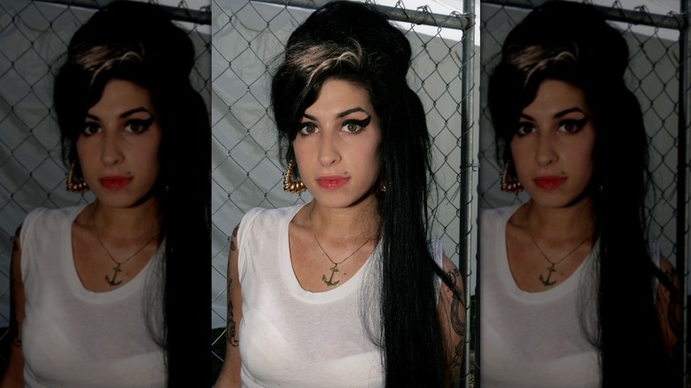 Amy Winehouse looking into the camera while wearing her signature chunky eyeliner and beehive hairstyle