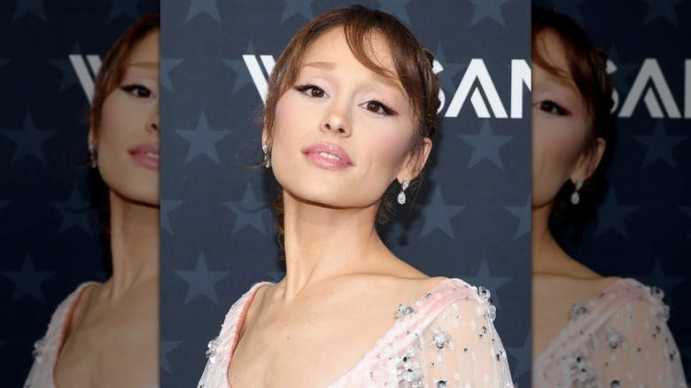 Ariana Grande looking into the camera sporting her hair in an updo and a winged eyeliner look
