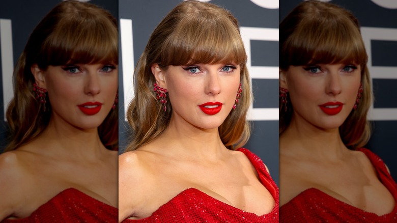 Taylor Swift posing at a red carpet event while wearing winged eyeliner and a bright red lip color