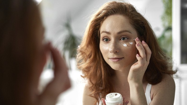 woman applies moisturizer