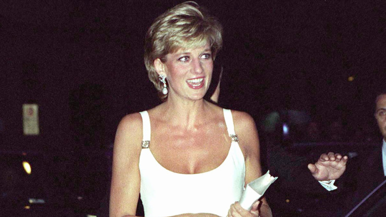 Princess Diana sitting on a step in a pink sweater and checkered pants in 1986