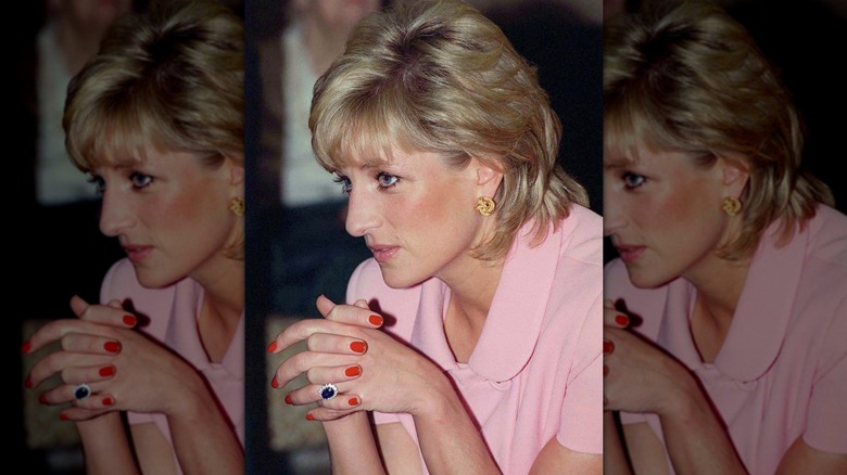Close-up of Princess Diana lacing her fingers in front of her while wearing a red manicure on her nails