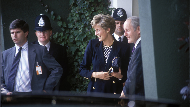 Princess Diana walking and wearing a black blazer with gold buttons