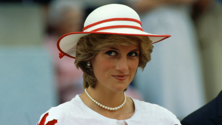 Princess Diana wearing a white and red hat along with a string of pearls