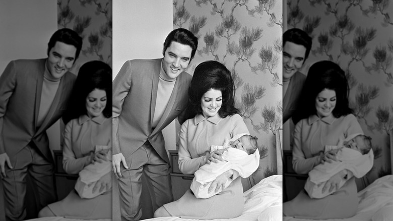 Elvis Presley stands next to Priscilla Presley holding Lisa Marie
