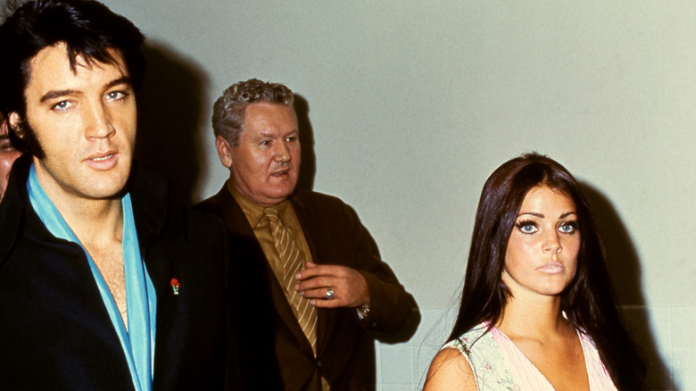 American singer Elvis Presley (1935 — 1977) walks with his wife, actress Priscilla Presley and father Vernon Presley circa 1970