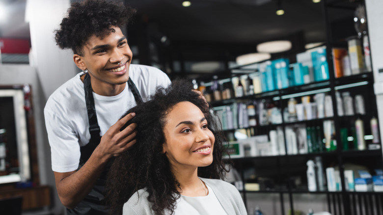 Black woman getting styled by hairdresser