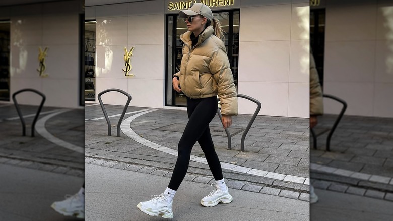 A woman in a puffer jacket with sneakers and leggings