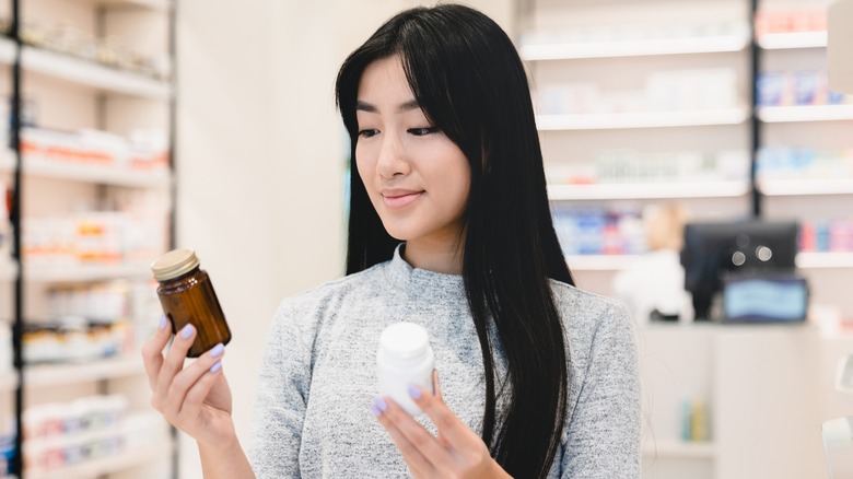 Woman comparing vitamin bottles