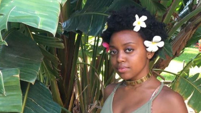 Quinta Brunson with flowers in her hair, posing in front of plants in 2016