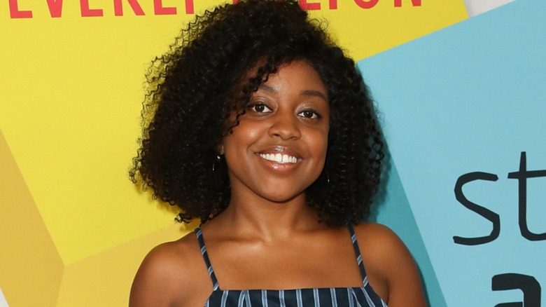 Quinta Brunson smiling on the red carpet in front of a multi-colored background in 2017