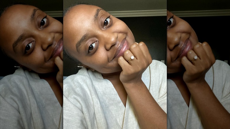 Quinta Bunson smiling and posing with her hand on her chin, showing her engagement ring